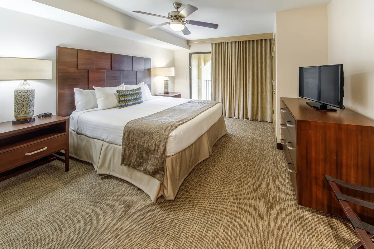 This image showcases a serene master bedroom featuring a plush king-sized bed, elegant wooden furniture, a large window that lets in natural light, and a television. The relaxed atmosphere and comfortable layout invite guests to unwind after a long day.