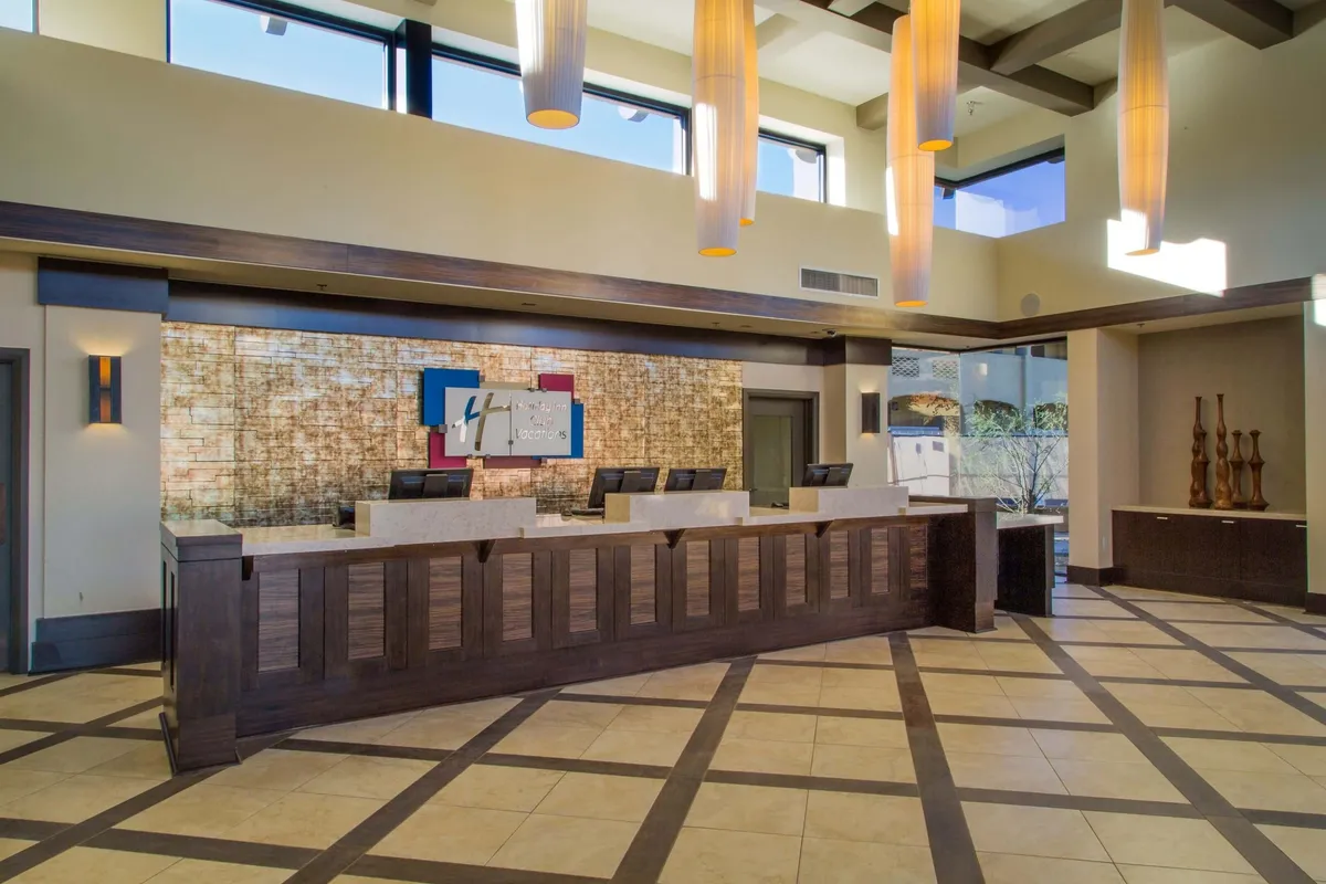 The resort's well-appointed interior reception area is warmly lit, with a welcoming desk, decorative wall art, and modern light fixtures. The scene conveys a sense of hospitality and attentive guest service as guests check in or seek information.